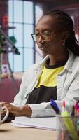 Vertical Woman in home office stretches back, feeling fatigued while working on laptop. Remote employee in apartment feeling backpain, relieving pain, solving tasks on notebook, camera A video