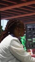 Vertical Teleworking computer scientist at home using PC to develop artificial intelligence self learning algorithms. African american woman working with AI machine learning software on PC, camera A video