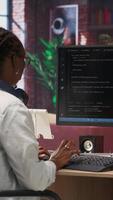 Vertical Admin uses computer for artificial intelligence computing simulation, waiting for code to finish compiling. African american woman works with AI deep neural networks at home, camera B video