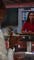Vertical Remote employee in teleconference meeting with manager, answering inquiries. Friendly freelancer in home office sitting at desk in front of computer screen, greeting supervisor in videocall, camera A video