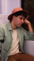 vertical close-up of tired traveler with hat asleep resting on window during long journey video