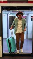 vertical happy traveler with hat smiling and waving at camera while getting off train with luggage video