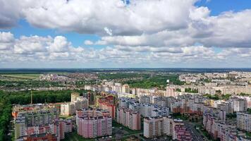 Urban background under beautiful sky. Modern city with high-rise buildings on green fields background. Aerial view. Camera rising up. video