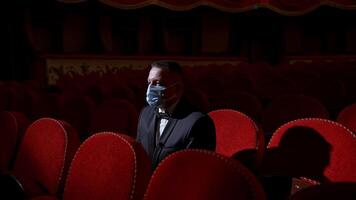 Kyiv, Ukraine, 29 May 2024 Man sits in the middle of empty theater hall with red velvet chairs. Actor is alone in theater. Lockdown and pandemic concept. video