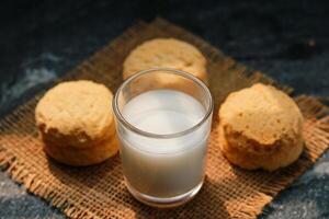 Milk in glass and cookies on the table, closeup of photo front view