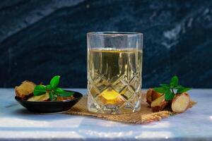 Ginger tea with mint in a glass on a Black tile photo