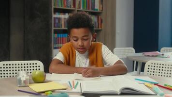 African American little boy ethnic child son pupil writing copybook schoolboy class school education homework task learn tired kid student yawning boring lesson studying learning at desk yawn sleepy video
