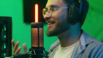 Close up happy smiling streamer radio host presenter Caucasian man businessman business male guy computer gamer cyber stream talking microphone streaming web at home dark evening neon wear headphones video