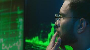 Indian Arabian man programmer hacker thinking looking computer chart guy trader analysis trading crypto currency database male technology IT specialist thoughtful coder monitor finance brainstorming video