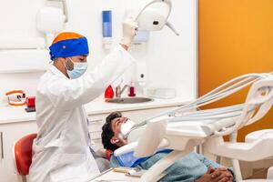 Dentist adjusting dental light while patient waiting for checkup in clinic photo