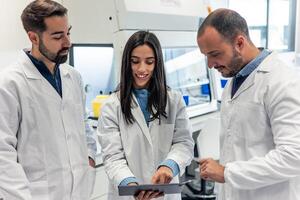 Scientists examining results on digital tablet in laboratory photo