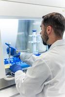 Scientist using micropipette and microplate inside laminar flow cabinet photo