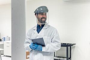 Scientist wearing face shield and holding tablet in laboratory photo
