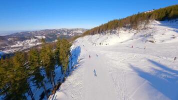 Smooth FPV flight over snowy mountain slope with people skiing and snowboarding. video
