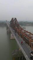 Aerial of traffic on historic Long Bien Bridge and Hanoi city skyline in Vietnam video