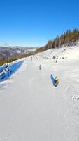 Smooth FPV flight over snowy mountain slope with people skiing and snowboarding. video