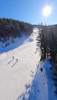 Smooth FPV flight over snowy mountain slope with people skiing and snowboarding. video