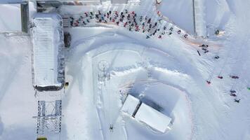 Aerial view of a queue of people waiting for a chairlift at a snowy ski slope video