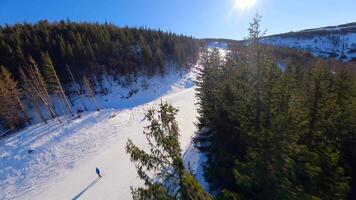Smooth FPV flight over snowy mountain slope with people skiing and snowboarding. video