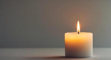Single lit candle with a golden flame casting a warm glow in a serene setting photo