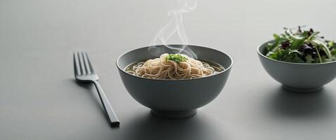 Noodles in a bowl with a fork and a bowl of salad photo