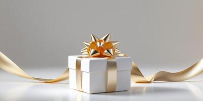 A small white gift box wrapped with a golden ribbon and tied with a shiny gold bow photo