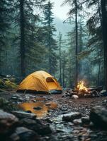 A serene camping scene with a yellow tent beside a campfire in a misty forest. photo