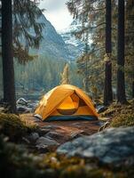 A serene camping scene featuring a yellow tent surrounded by tall trees and mountains. photo