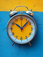 A colorful alarm clock with a yellow face and blue hands against a vibrant wall. photo