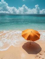 A serene beach scene featuring an orange umbrella by the turquoise ocean. photo