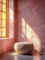 A serene interior scene featuring a round stone bowl and warm sunlight through a window. photo