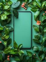A smartphone surrounded by green leaves and flowers on a solid background. photo