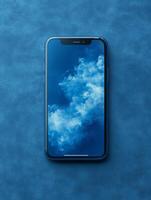 A smartphone displaying a blue cloud wallpaper on a textured blue surface. photo