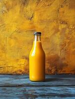 A glass bottle filled with orange liquid against a textured yellow background. photo