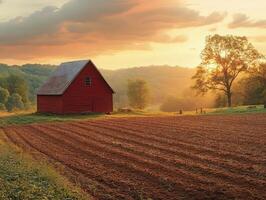 A serene sunset over a red barn and freshly plowed field in a rural landscape. photo