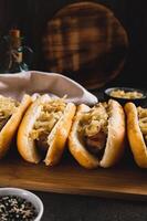 Homemade hot dogs with caramelized onions on a board on a table vertical view photo