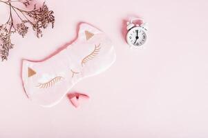 Concept insomnia sleep mask, earplugs and alarm clock on pink background photo