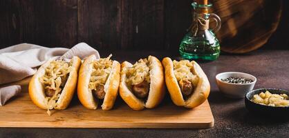 Homemade hot dogs with caramelized onions on a board on a table web banner photo