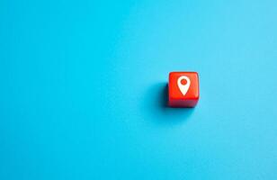 Red block with geolocation symbol on a blue background. Search for new places to travel. Guide on interesting destinations. Advertising and awareness. photo