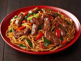 Deliciously cooked beef stir-fry with noodles and vegetables on a red plate photo