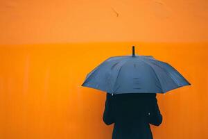 A Person Holds a Black Umbrella Against an Orange Wall During a Rainy Day, Showing Minimalist Street Photography Aesthetics, Featuring a Monochromatic Color Scheme and Striking Contrast photo