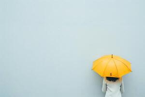 A Person Holds a Yellow Umbrella Against a Light Blue Wall. A Study in Minimalist Photography, Evoking Feelings of Calm and Solitude, Perfect for Relaxation and Contemplation. photo