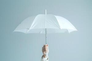 A Hand Holds a White Umbrella Upward Against a Light Blue Sky, Providing Shade and Protection from the Elements, Symbolizing Hope and Resilience During Life's Storms photo