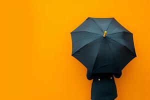 A Person Holds a Black Umbrella Against a Vibrant Orange Background, Creating a Striking Contrast and Evoking a Sense of Mystery and Protection. This Visual Metaphor Represents Resilience photo