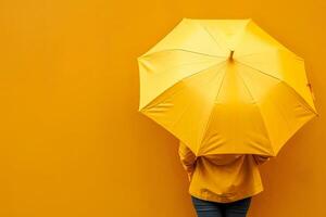 A Person Stands with Yellow Umbrella and Raincoat Against a Yellow Wall. A Study in Color and Minimalism, Exploring Monochromatic palettes and Moods. photo