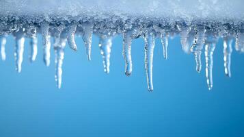 Long icicles hang from roof edge against crystal clear blue sky, displaying frozen water droplets and transparent ice formation with dramatic natural lighting in winter scene. formation photo