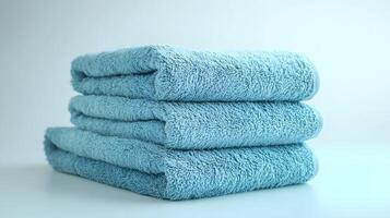Soft blue cotton towels stack neatly folded, showcasing plush luxury bathroom textiles with high-quality fabric texture in pale blue theme, creating spa-like atmosphere against white background. blue photo
