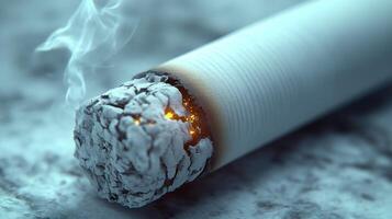 A cigarette smolders quietly, exhaling wisps of smoke into the cool air photo