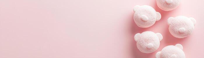 Cute child-friendly bath bomb background featuring teddy bear shapes in soft pastel tones on a smooth light pink surface with ample space for text photo