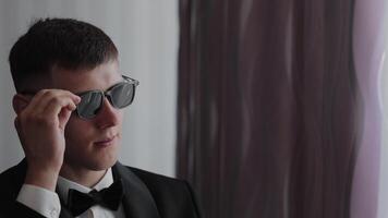 Groom in Black Suit Adjusting Sunglasses, Groom in a sharp black tuxedo with a bow tie adjusts his sunglasses video